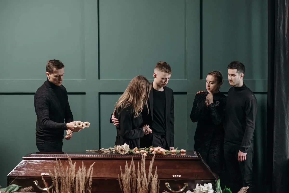 Family mourning beside a coffin at an indoor funeral.