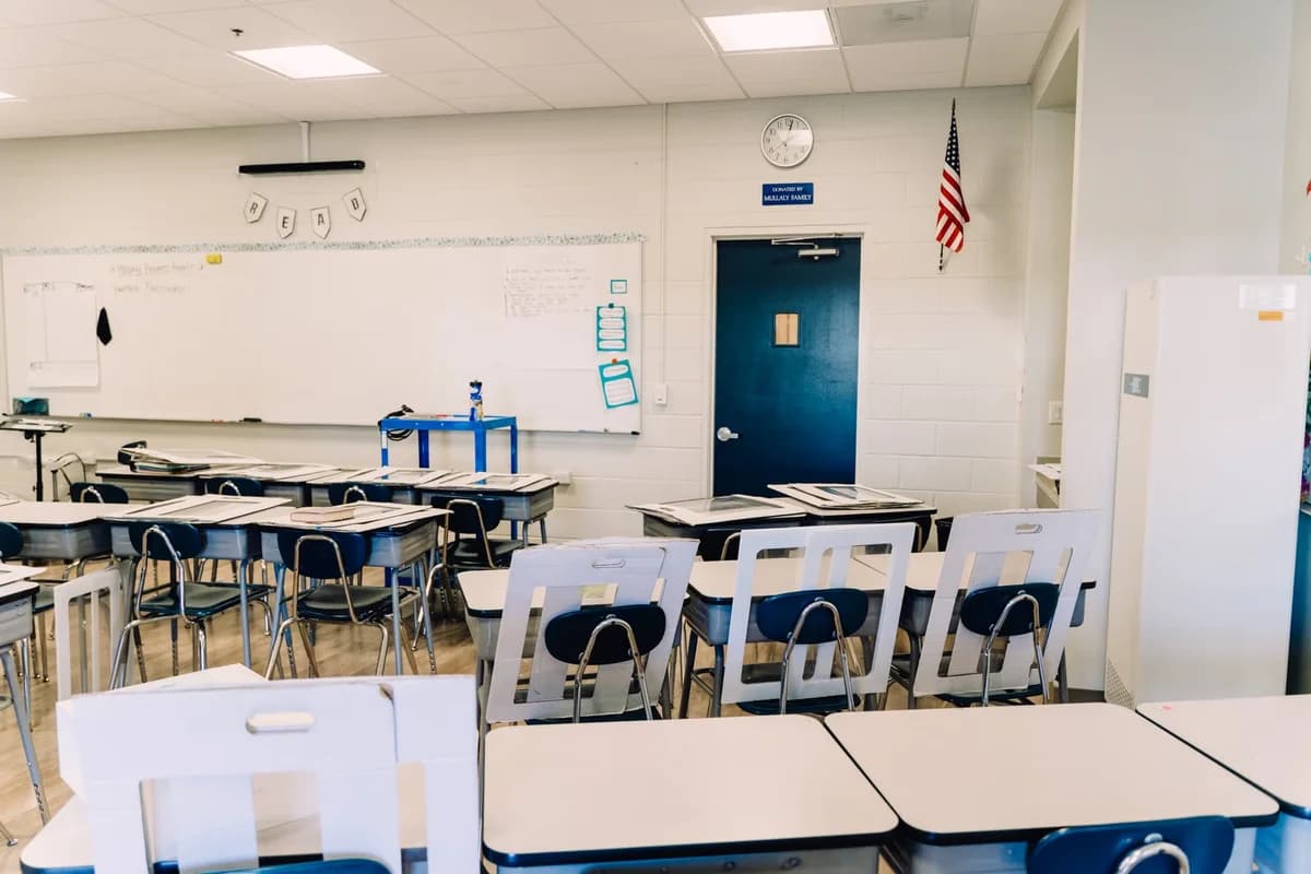 Empty classroom with desks, a whiteboard, and an American flag on the wall.