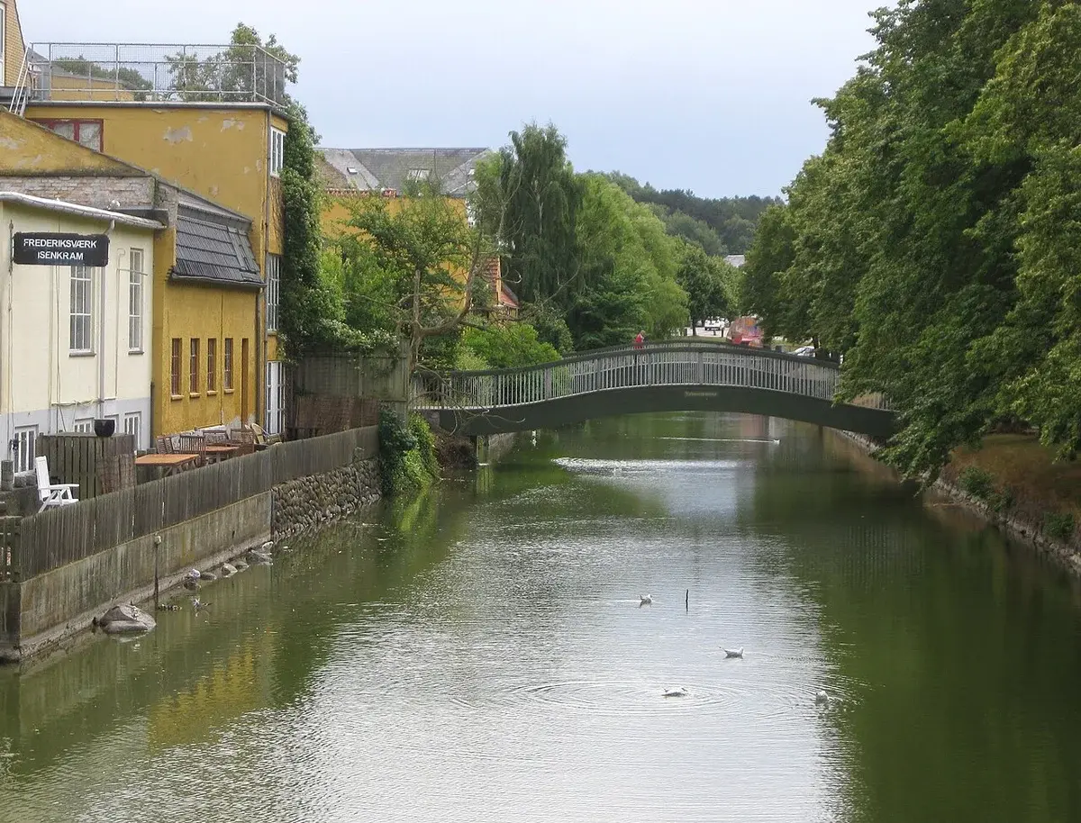 Canal scene in Frederiksværk with a bridge and trees.