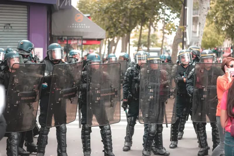 Soldiers in police uniforms with helmets and shields standing in formation