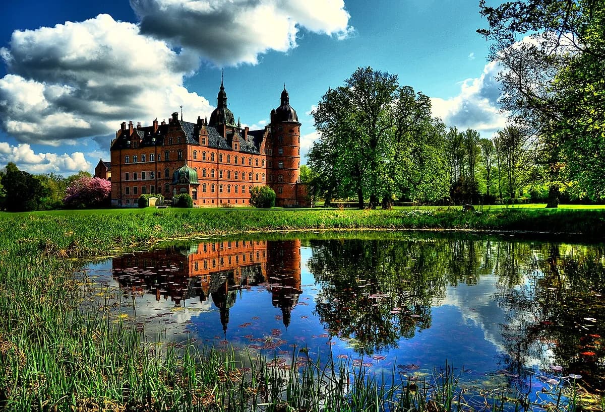 Egeskov Castle reflected in a moat on a sunny day.