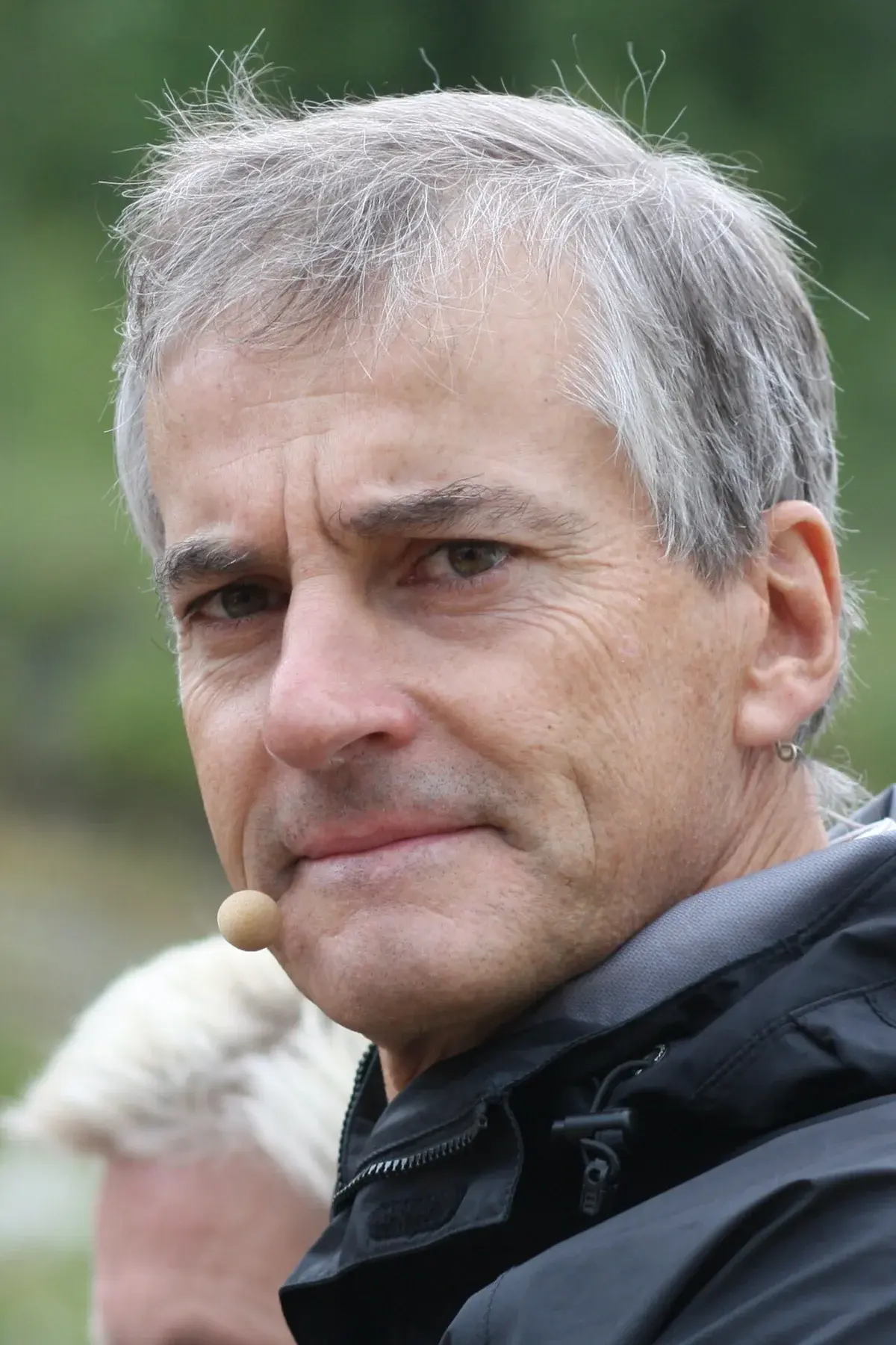 Close-up of Jonas Gahr Støre wearing a headset microphone outdoors.