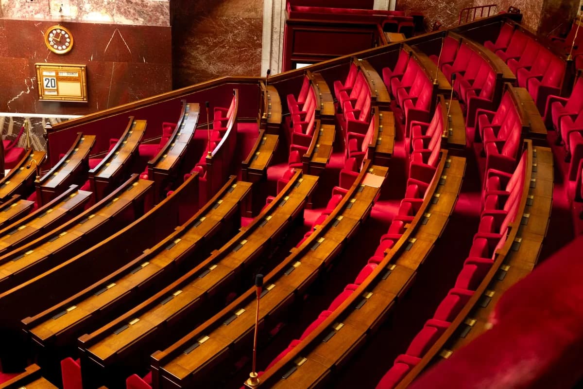 Curved rows of red seats and wooden desks in a legislative chamber.