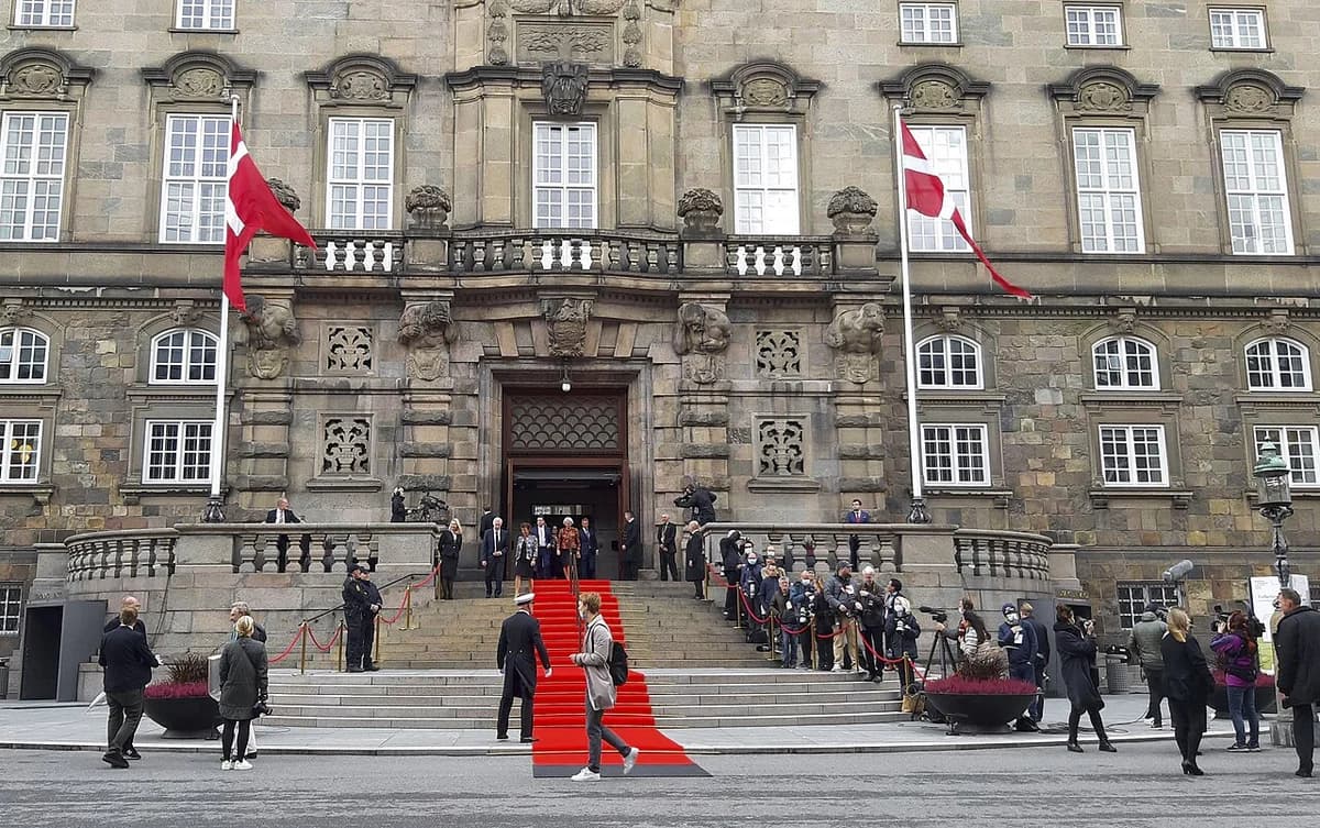 People gathered outside the Danish Parliament building with a red carpet on the steps.