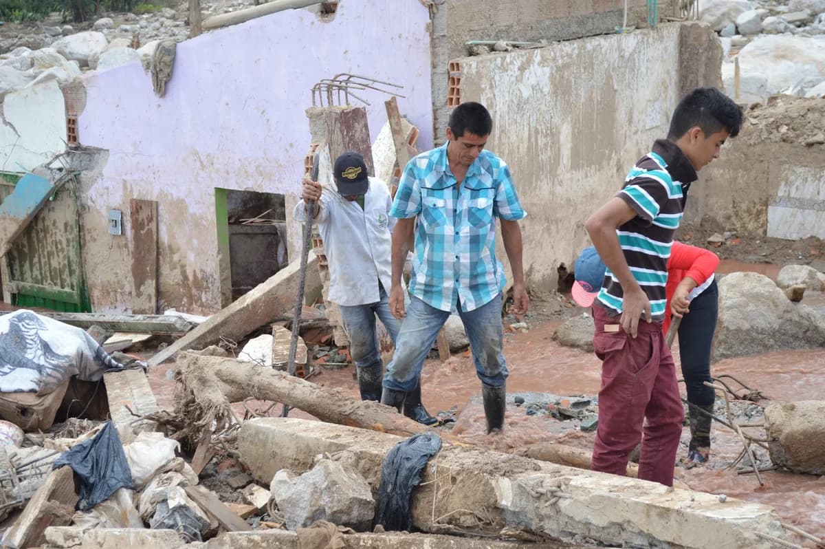 People walking through flood debris and damaged buildings in Mocoa.