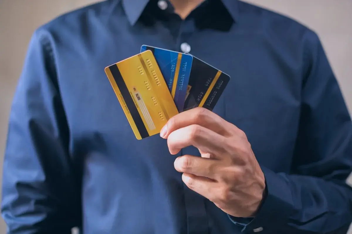 A person holding three credit cards.