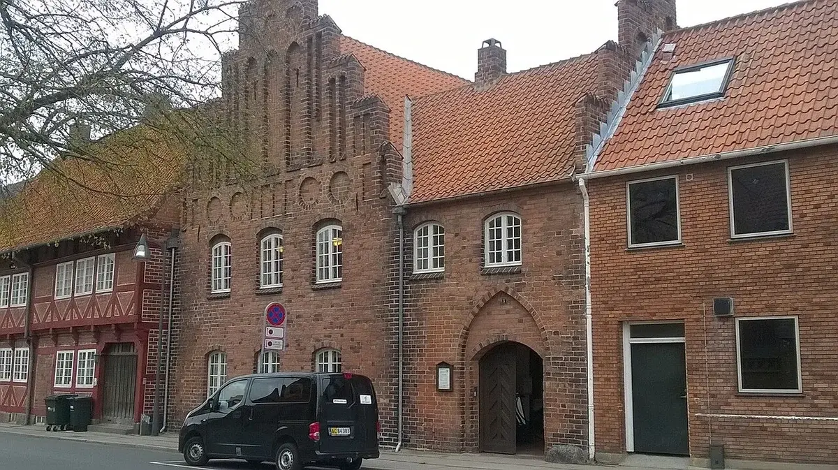 Historic brick town hall building on a street with a parked van.