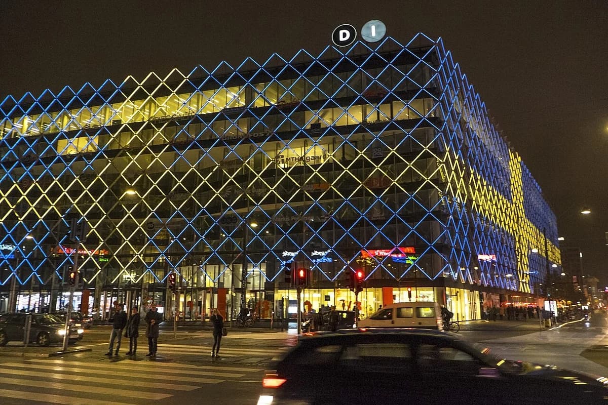 Night view of the Danish Industry building in Copenhagen lit in blue and yellow.