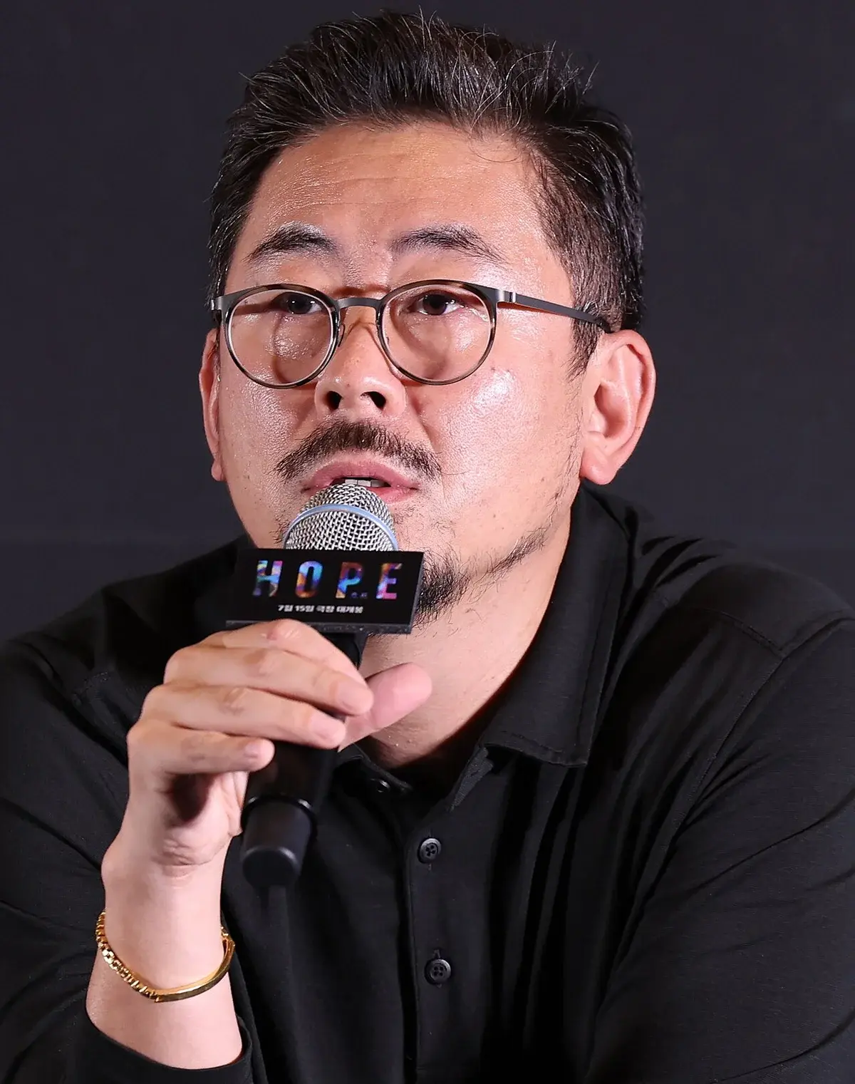 South Korean filmmaker Na Hong-jin speaking into a microphone at an event.