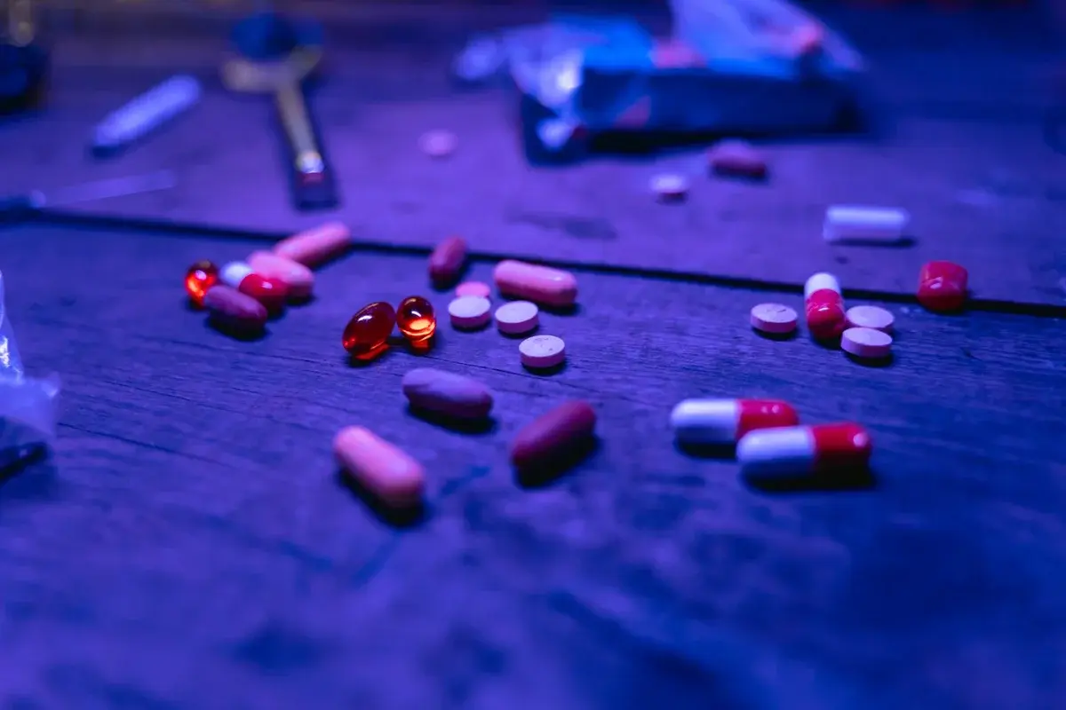 capsules and pills on wooden surface with blue light