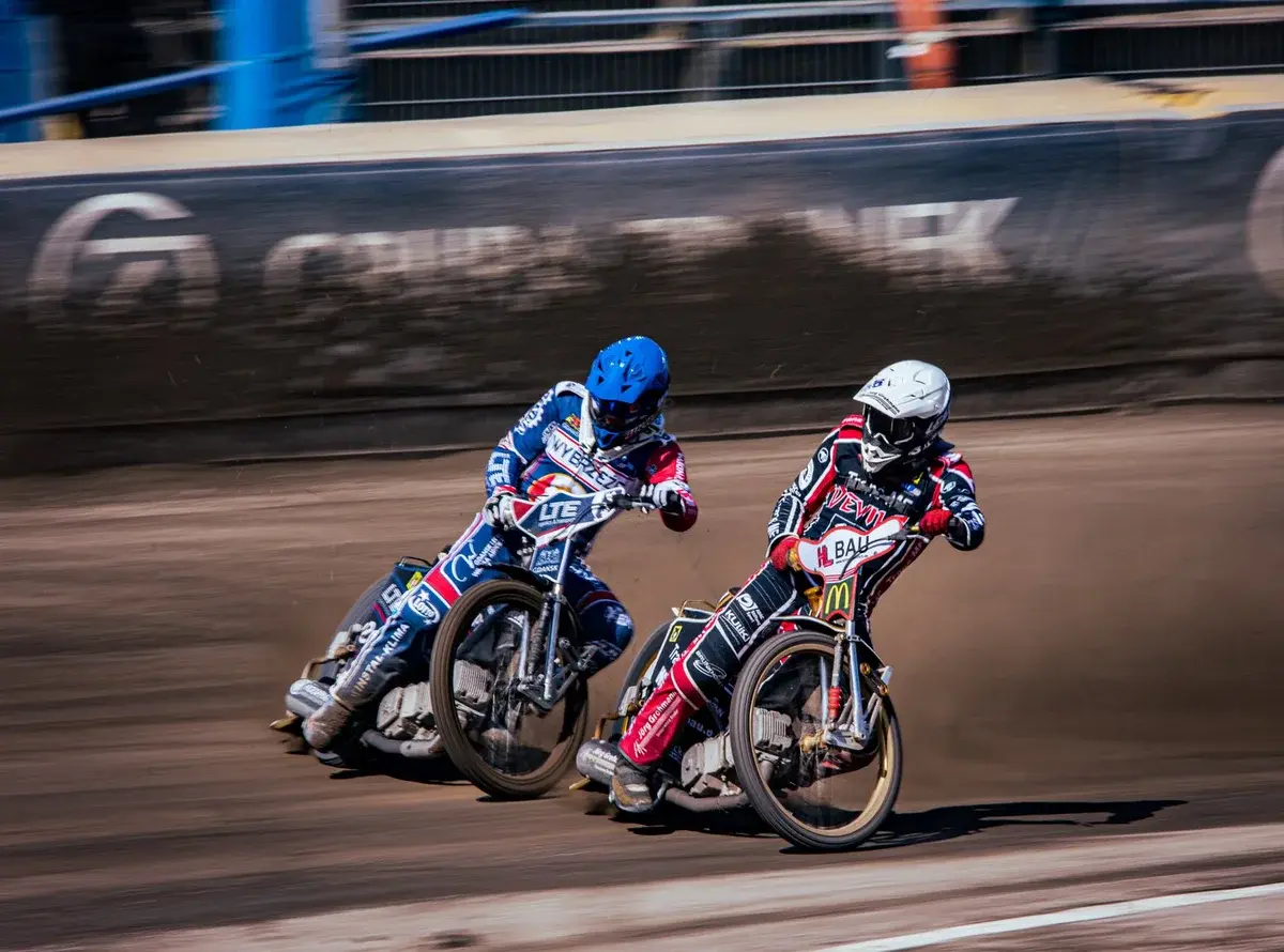 Two speedway motorcyclists racing on dirt track