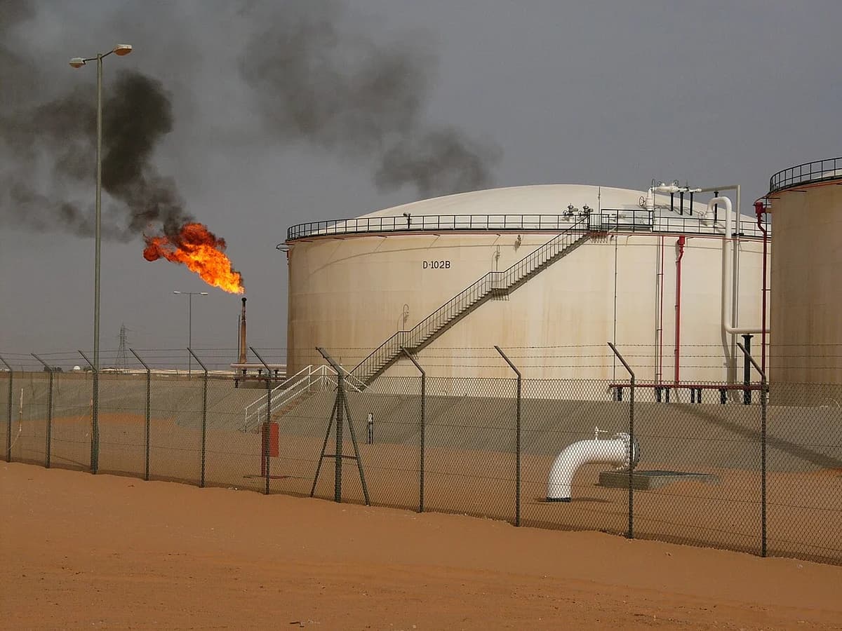 Oil tanks at a desert refinery with a gas flare burning.
