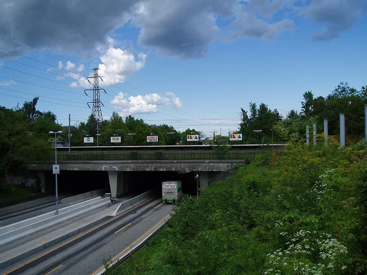 An elevated station over a roadway with a truck passing underneath.