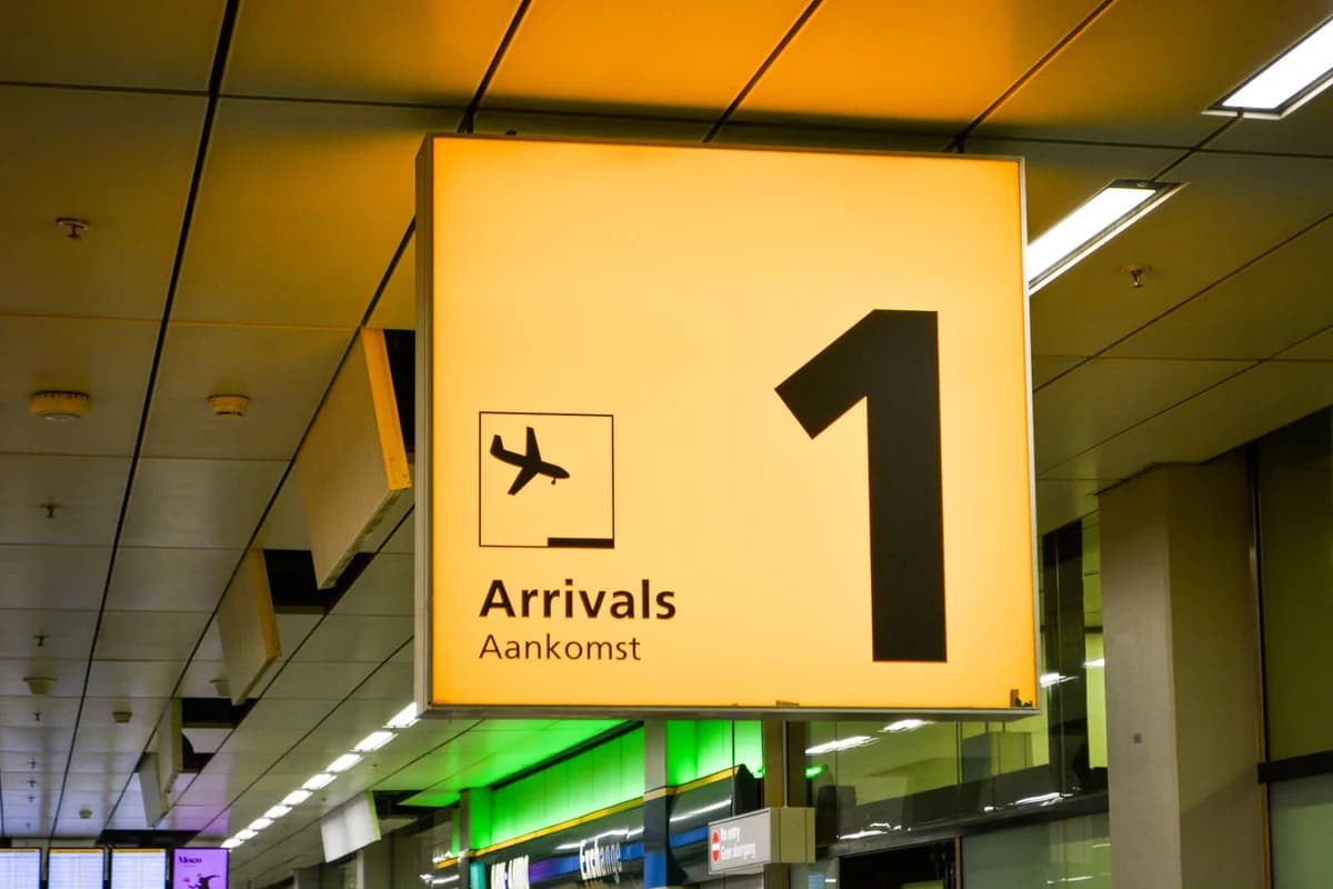 Illuminated airport arrivals sign with airplane icon and the number 1 in a terminal.