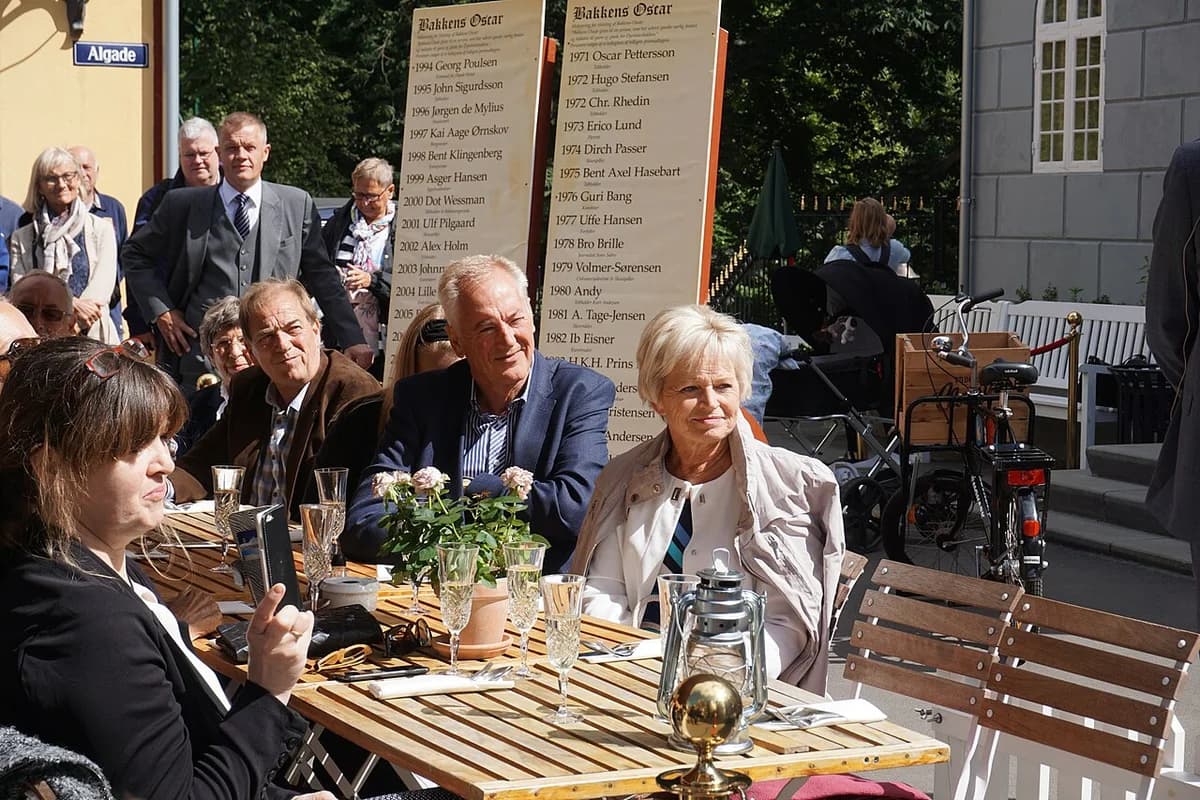 People seated outdoors at a Bakken event with winner boards in the background.