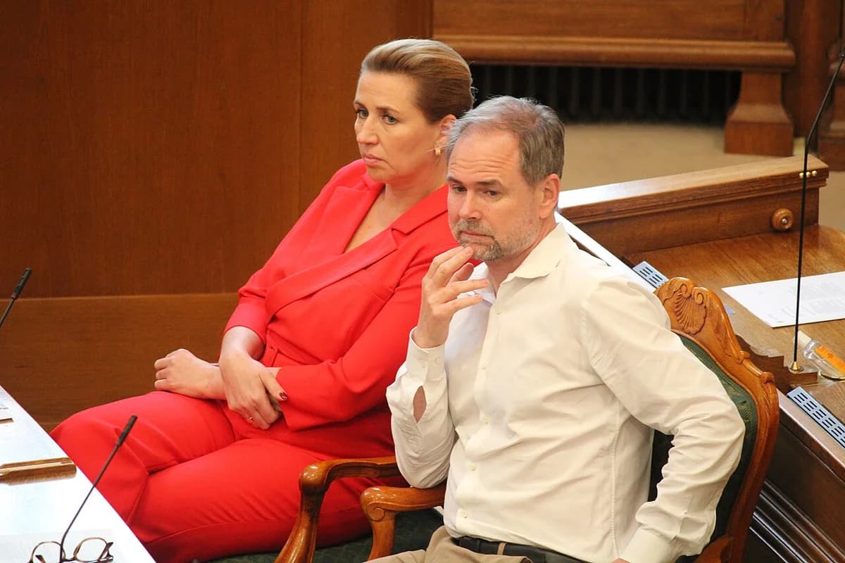 Mette Frederiksen and Nicolai Wammen seated in the Danish parliament chamber during a debate.