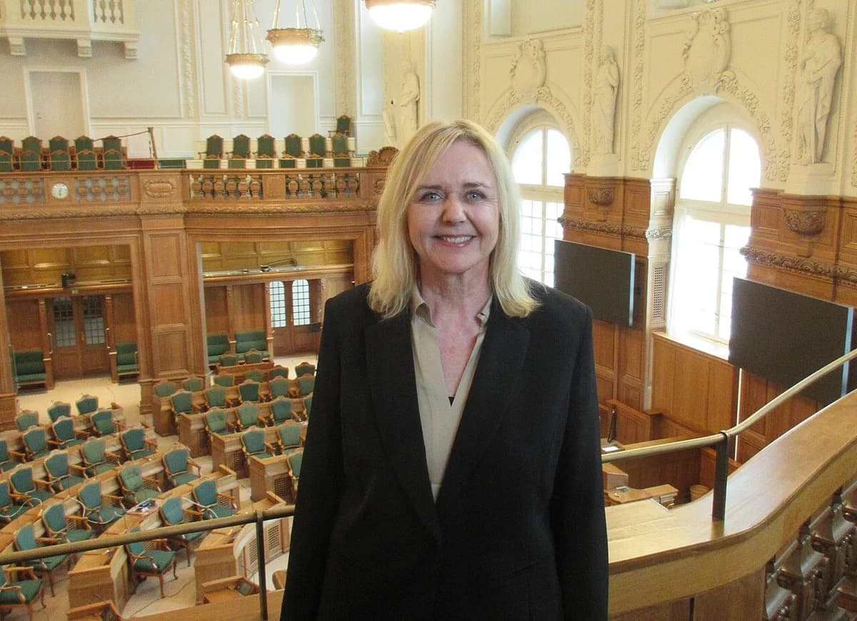 Mona Juul standing in the public gallery of the Danish Parliament.