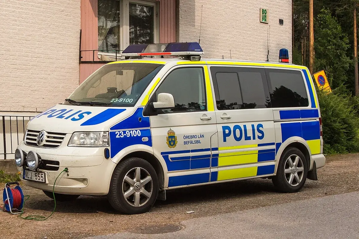 A Swedish police van with blue and yellow markings parked beside a building.