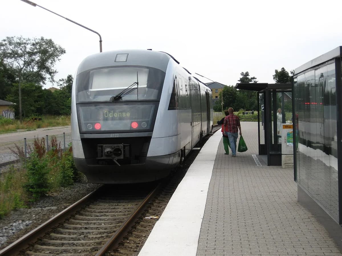 A modern train at a station platform with a few people nearby.