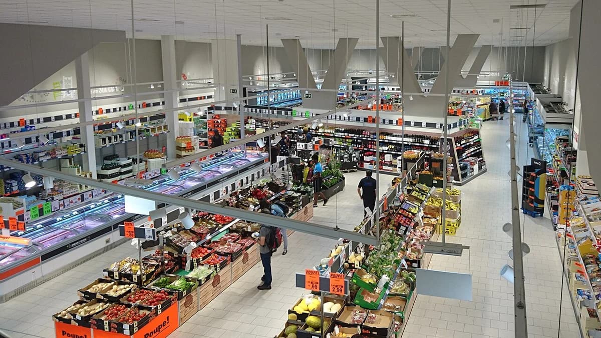 Interior of a Lidl supermarket with produce aisles and shoppers.