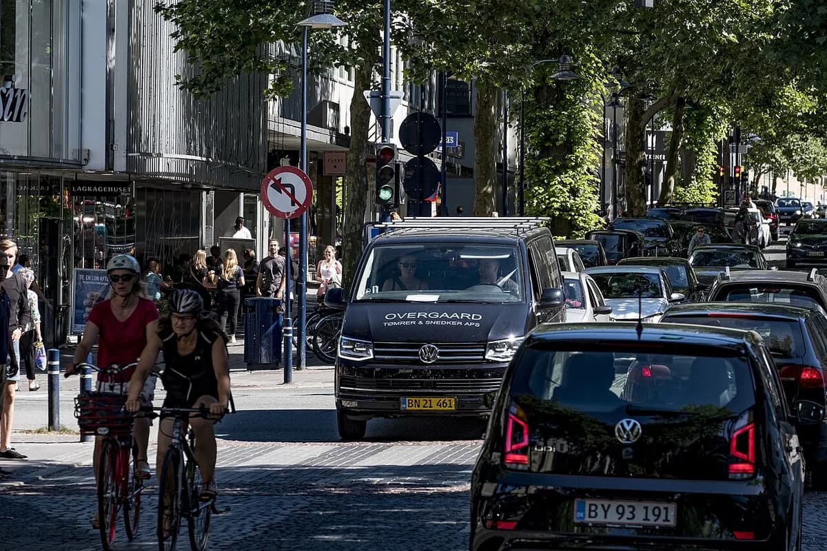 Busy street in Kongens Lyngby with cars, cyclists, and pedestrians.