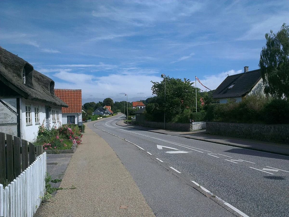 A quiet residential street curving through Jægerspris on a sunny day.