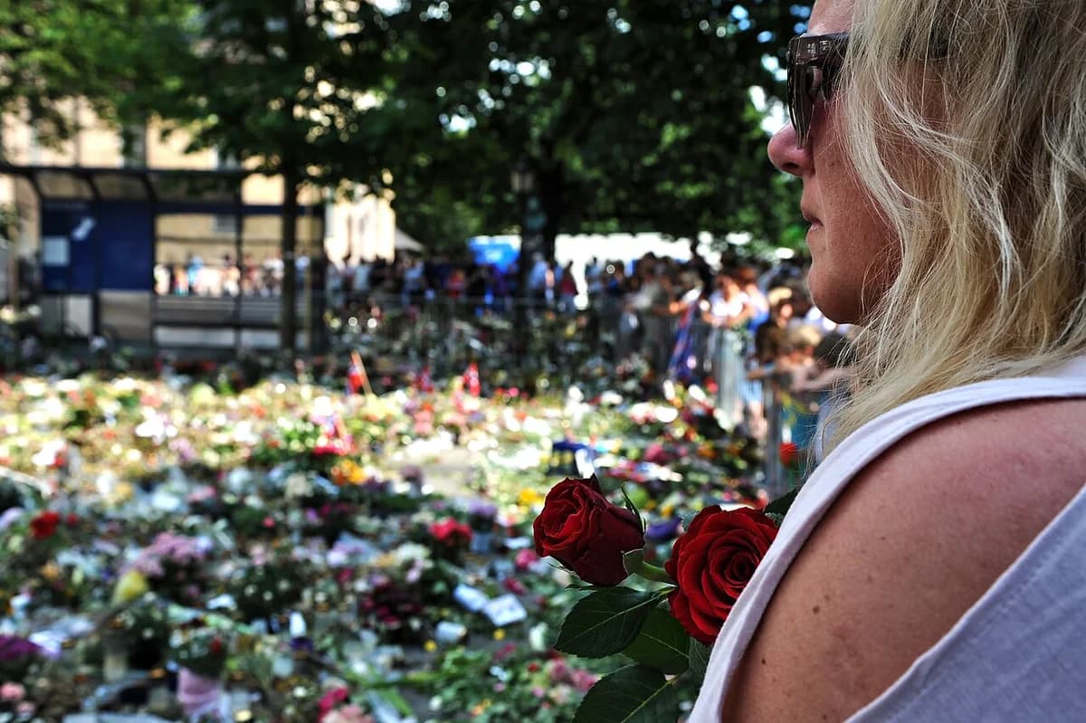 Woman holding roses at a crowded flower memorial