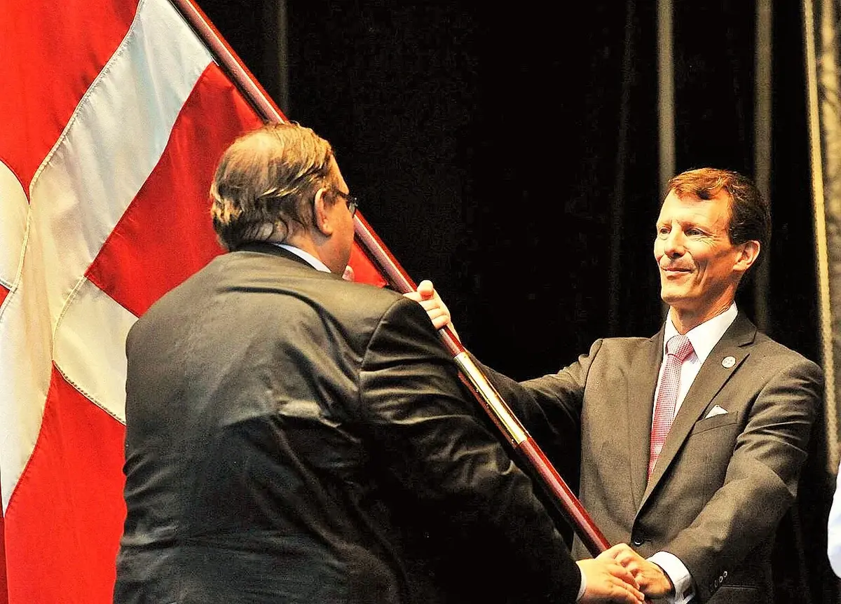 Prince Joachim of Denmark holding a Danish flag at an official event.
