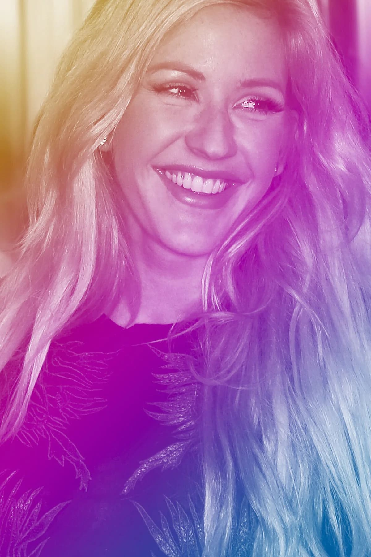 Close-up of Ellie Goulding smiling under pink and purple concert lights.