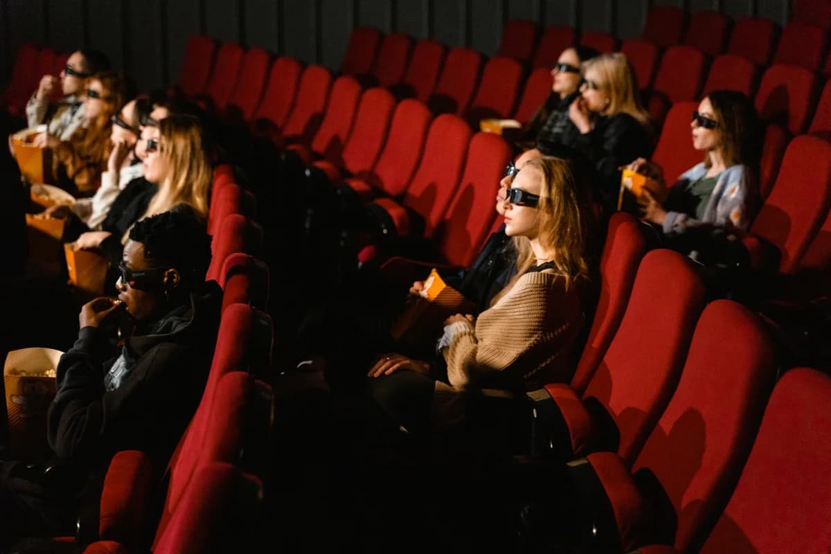 People in cinema seats wearing 3D glasses and eating popcorn