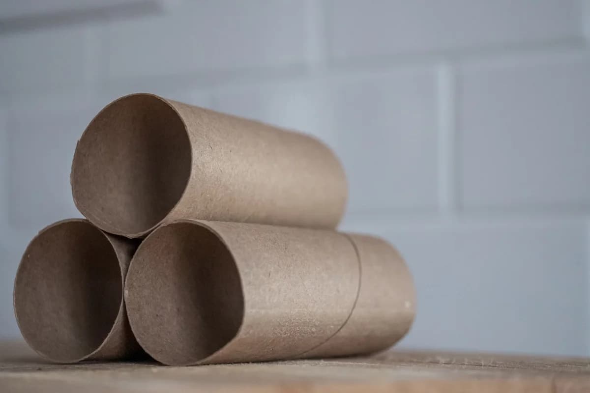 Close-up of stacked brown toilet paper cardboard tubes on a wooden table.