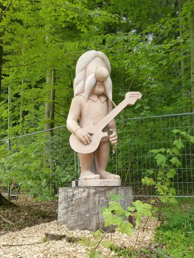 Wooden statue of a musician with an electric guitar outdoors
