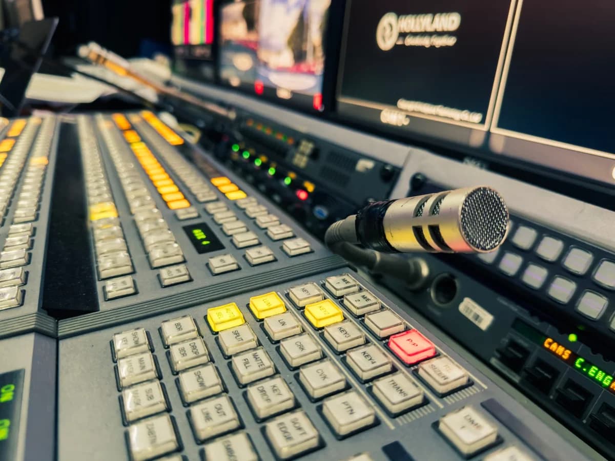 Close-up of a broadcast control panel with a microphone and studio monitors.