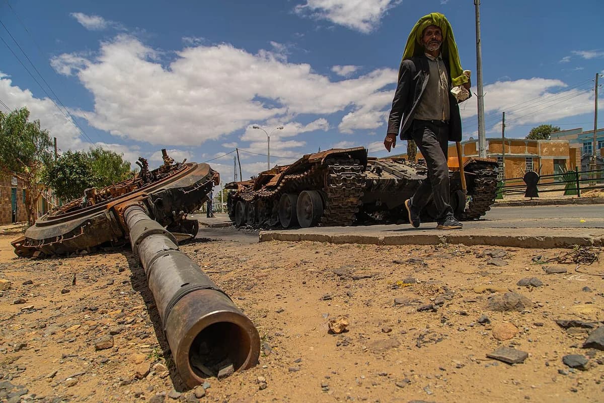 A man walks past a destroyed tank on a street in Edaga Hamus, Ethiopia.
