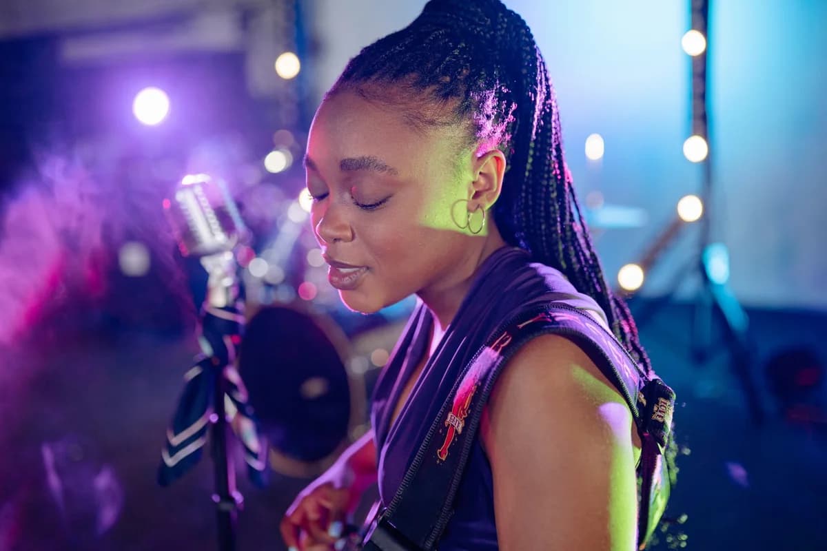 Black female performer on a colorful stage near a microphone