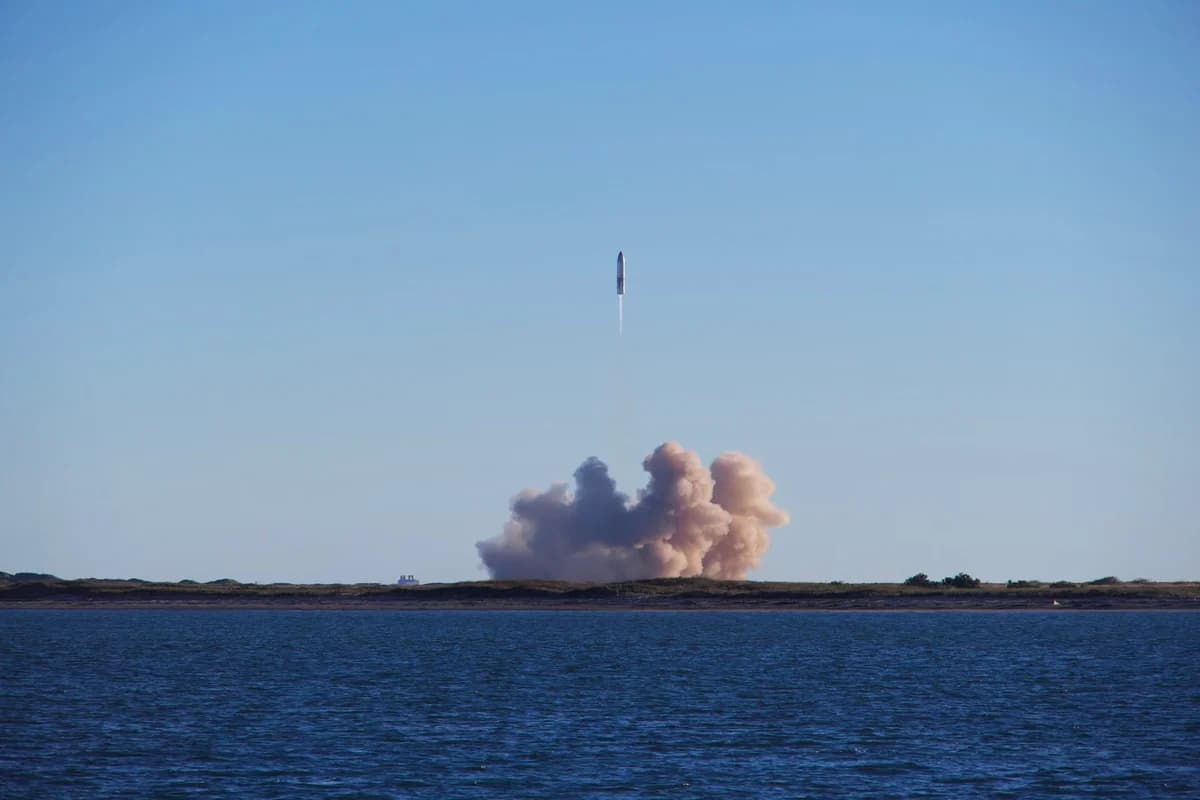 Rocket launching over coastal land with water in foreground