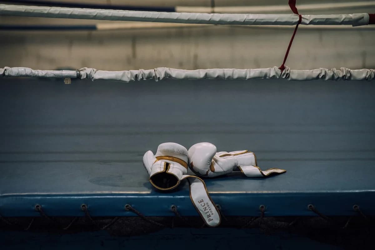 White boxing gloves lying in an empty boxing ring