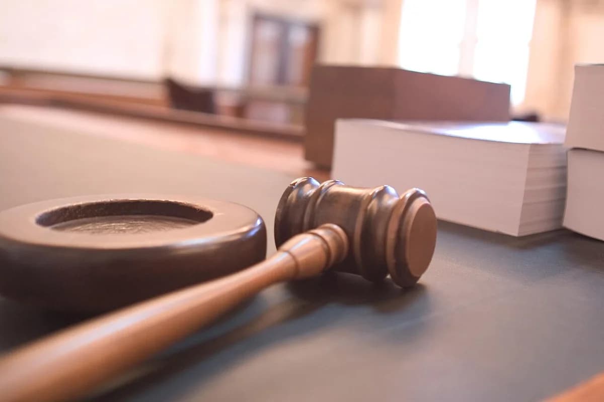 A judge's gavel on a courtroom desk with books in the background.