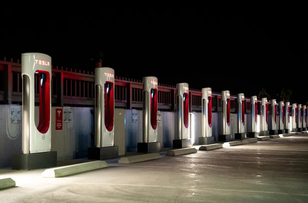 A row of illuminated Tesla charging stations at night.