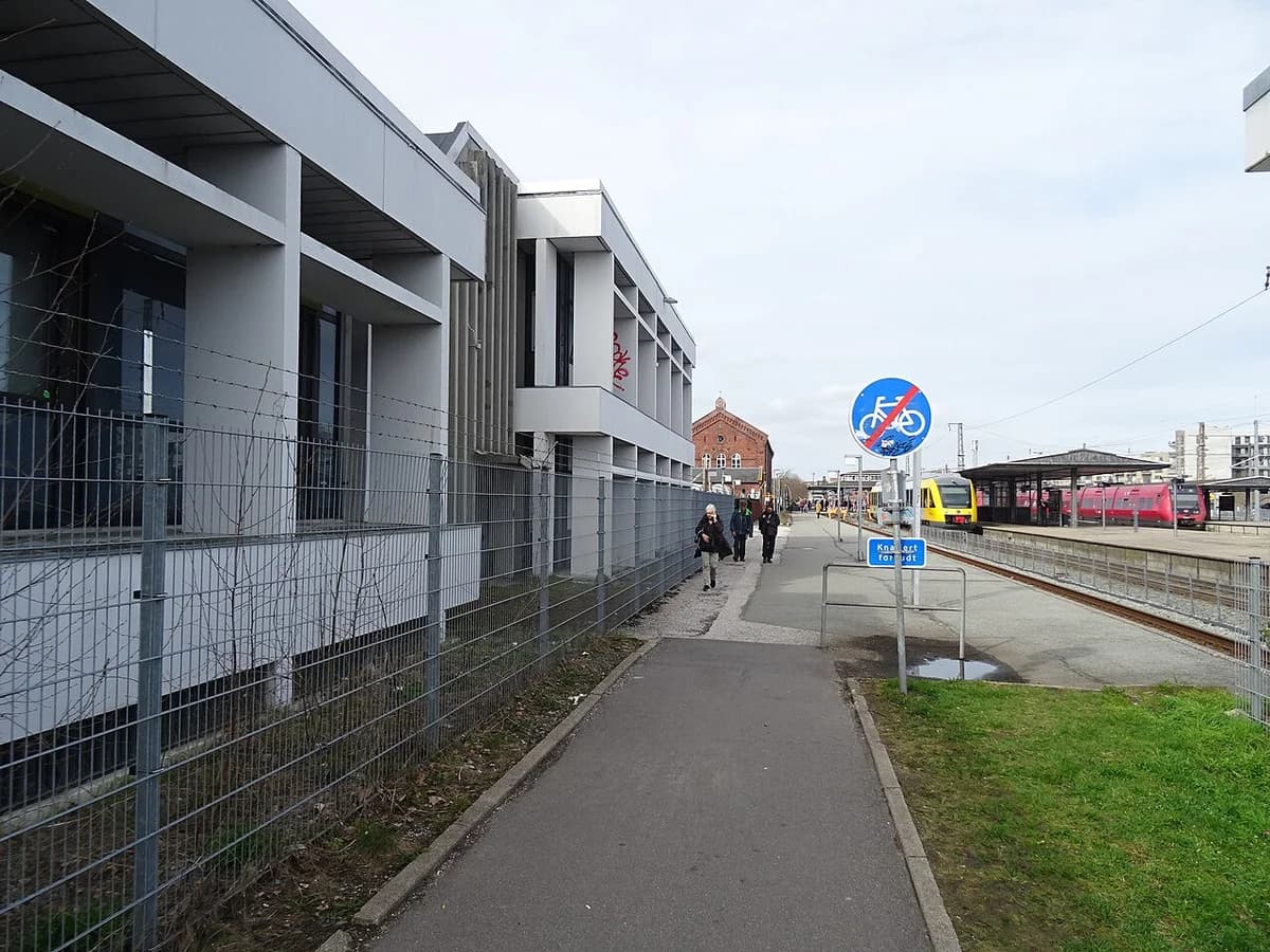 A bike path beside Hillerød Station with trains on the right and buildings on the left.