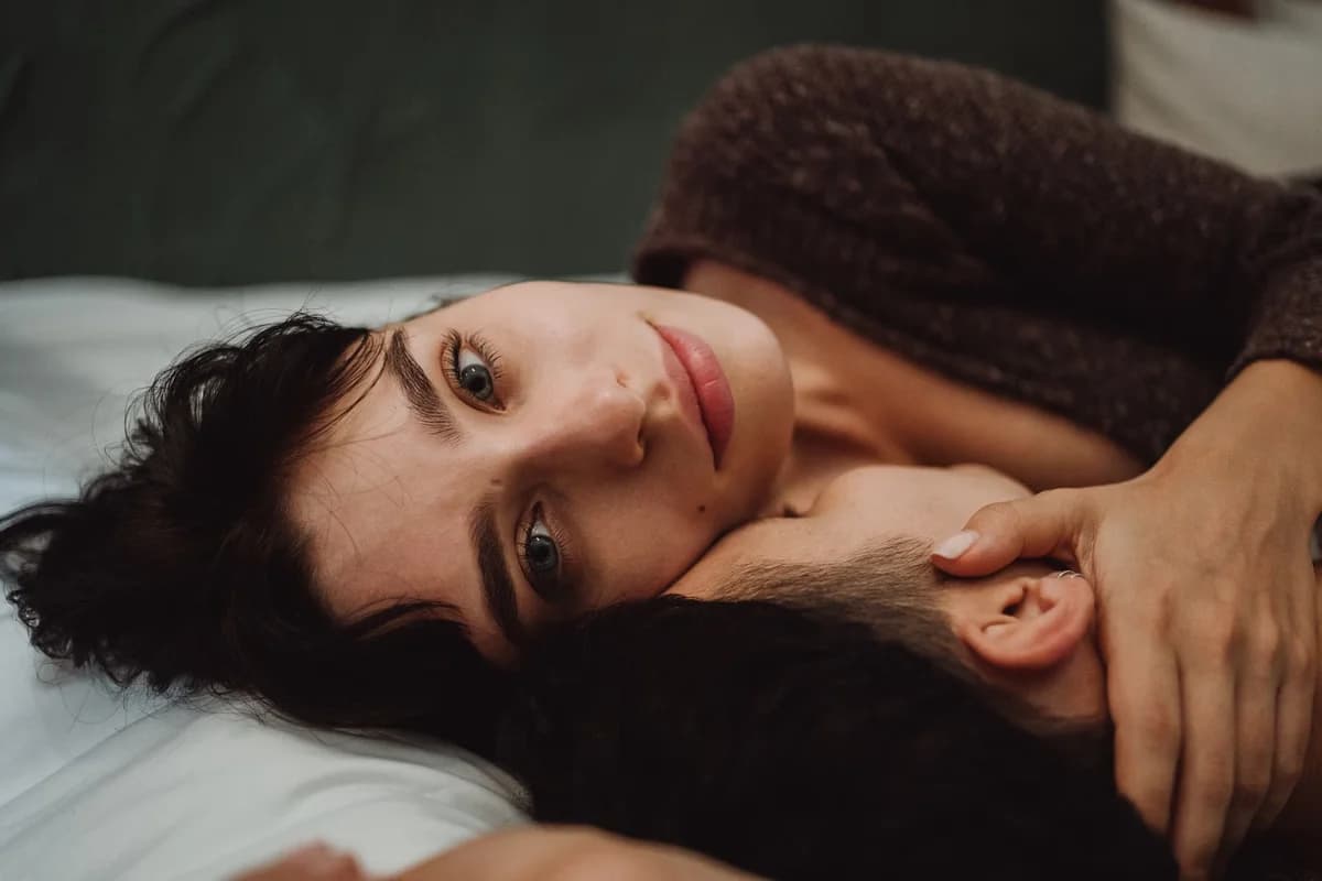 Close-up of a couple cuddling on a bed indoors.