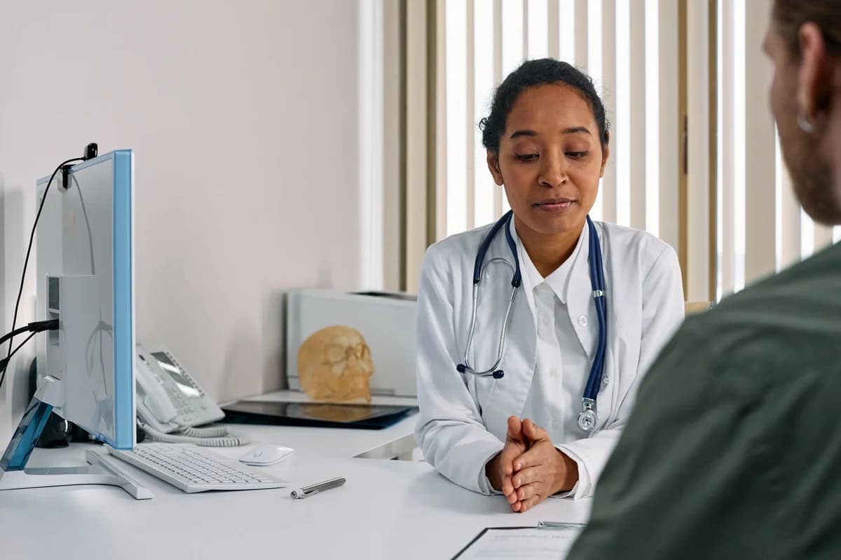 A female doctor speaks with a patient in a clinic office.