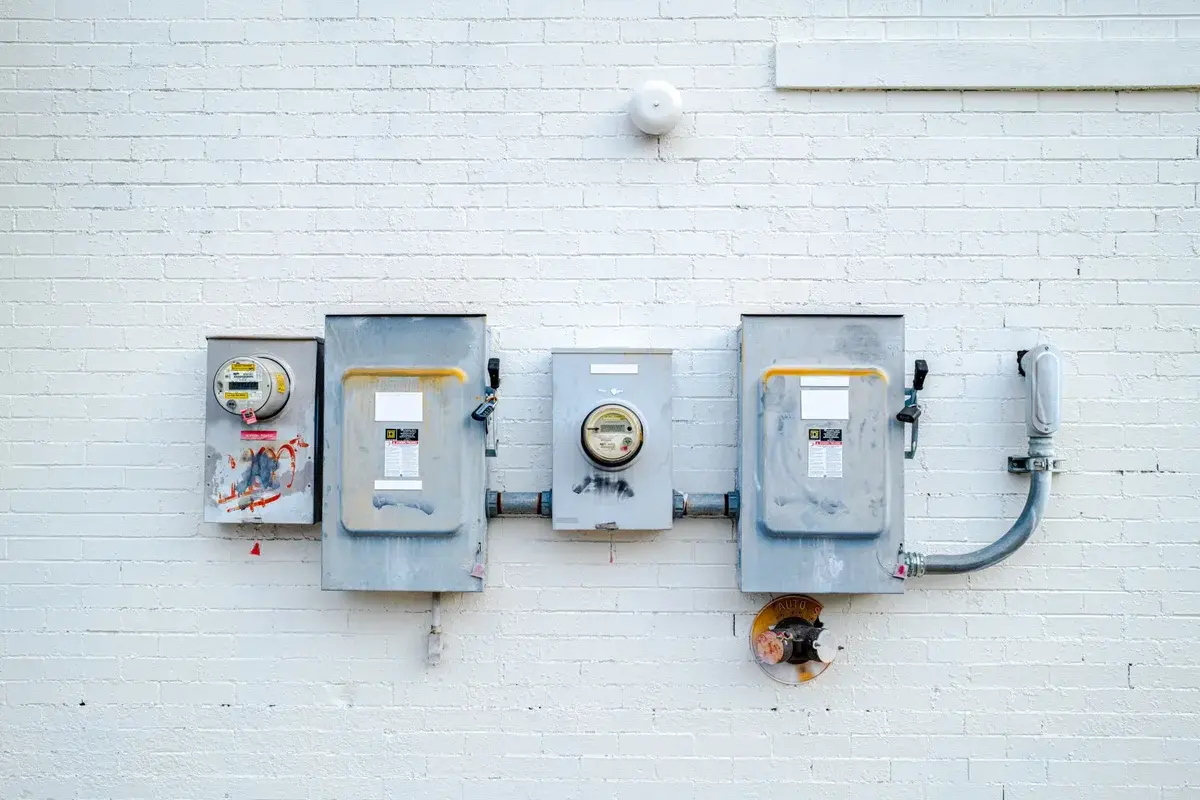 Electrical boxes and utility meters mounted on a white brick wall