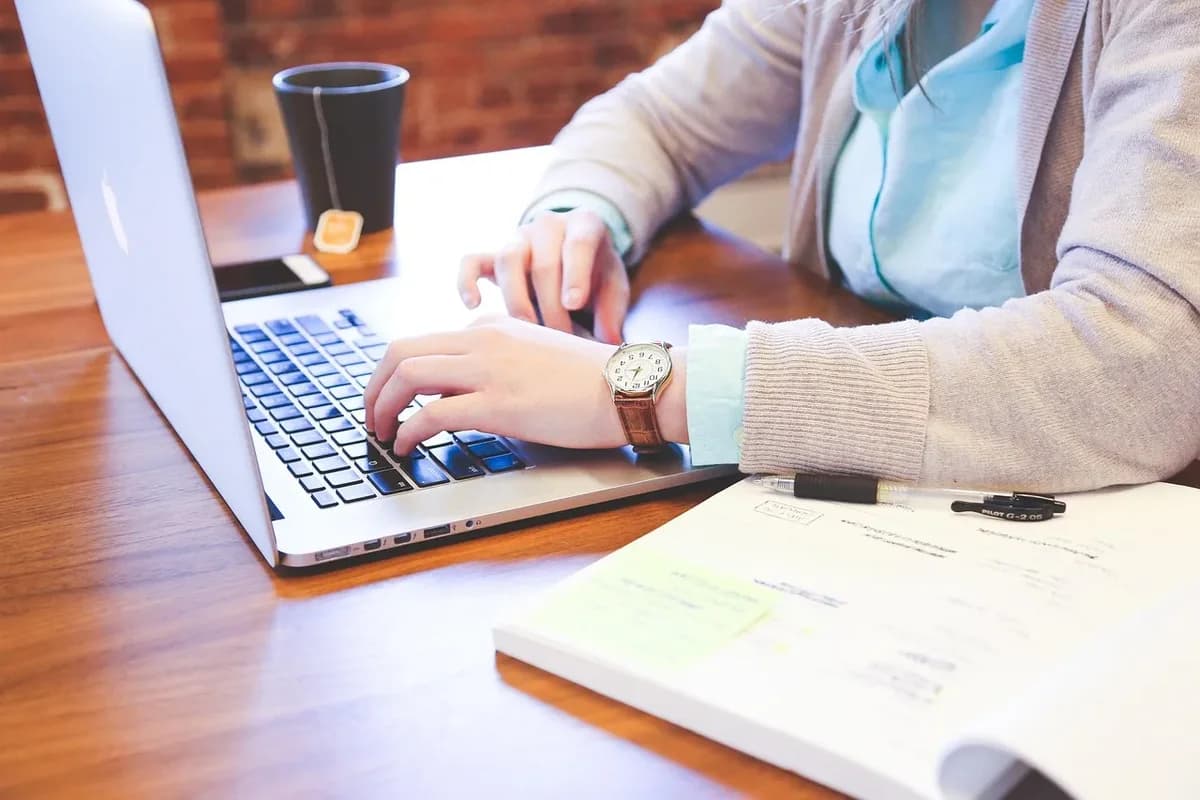student typing on laptop with documents nearby