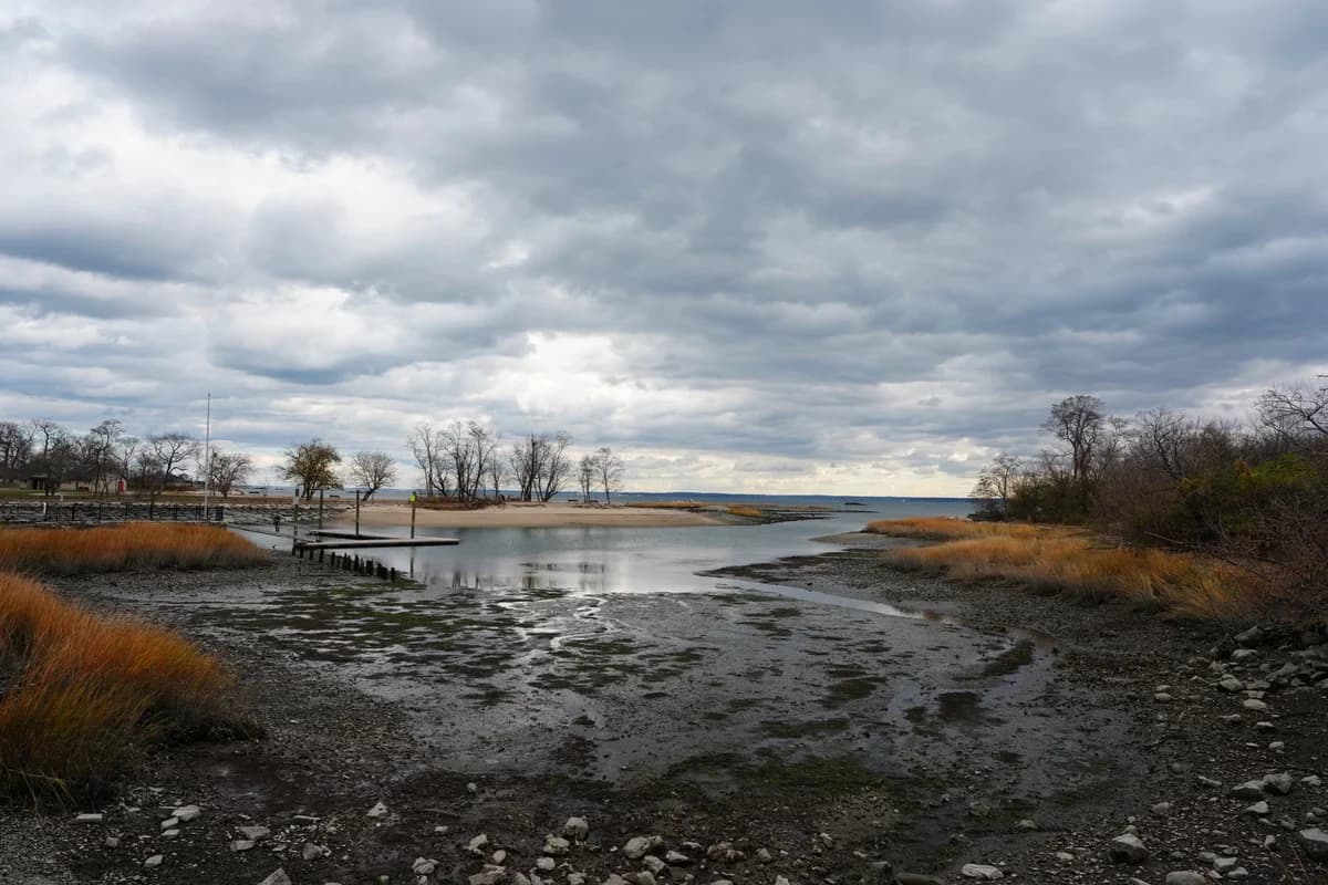Low-tide coastal landscape under dark storm clouds.
