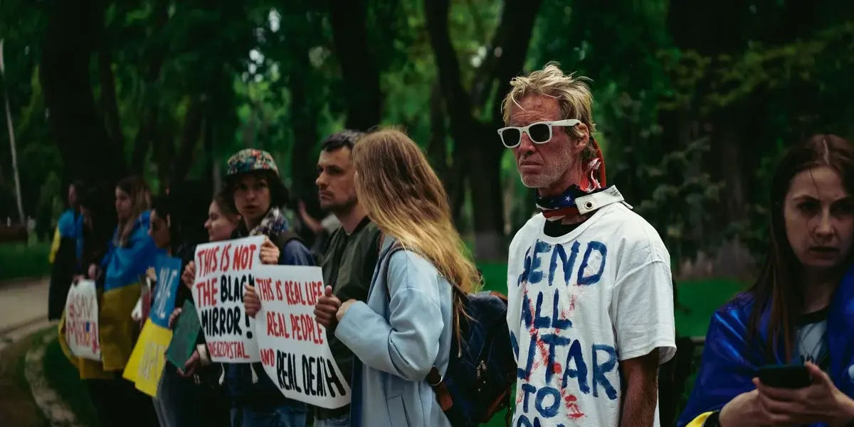 People holding protest signs in a park in Kyiv.
