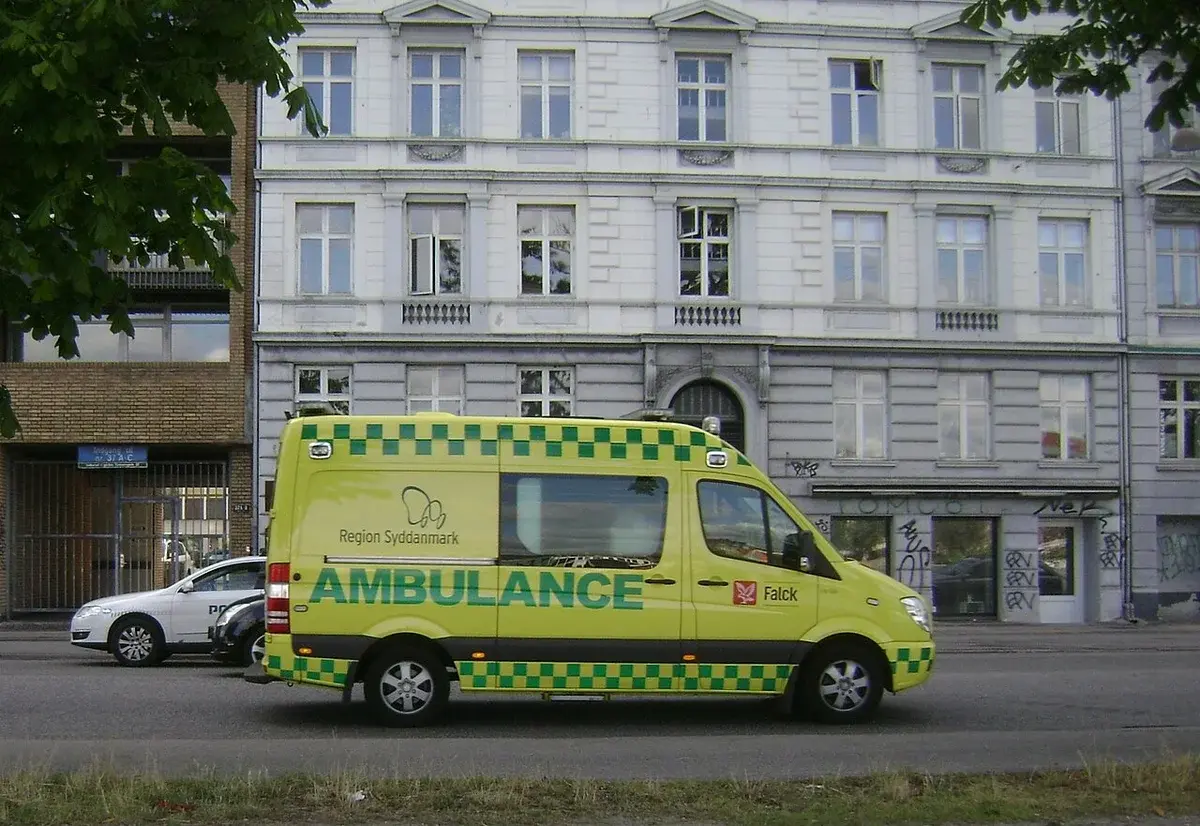 A Falck ambulance parked on a street in front of a white building.
