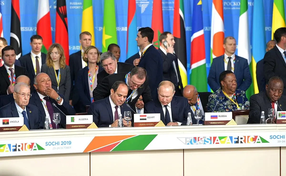 Delegates seated at a Russia-Africa summit table with flags behind them.