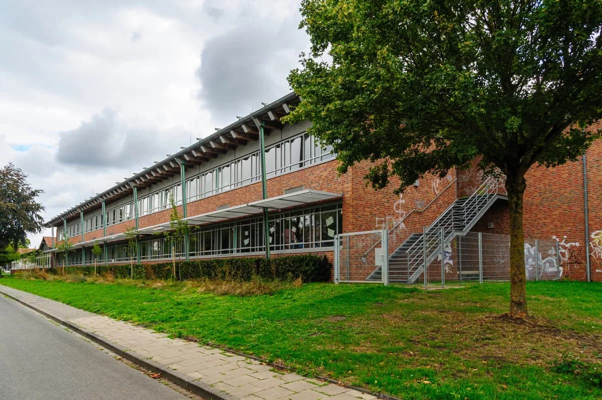 A modern brick school building with trees and grass beside it.