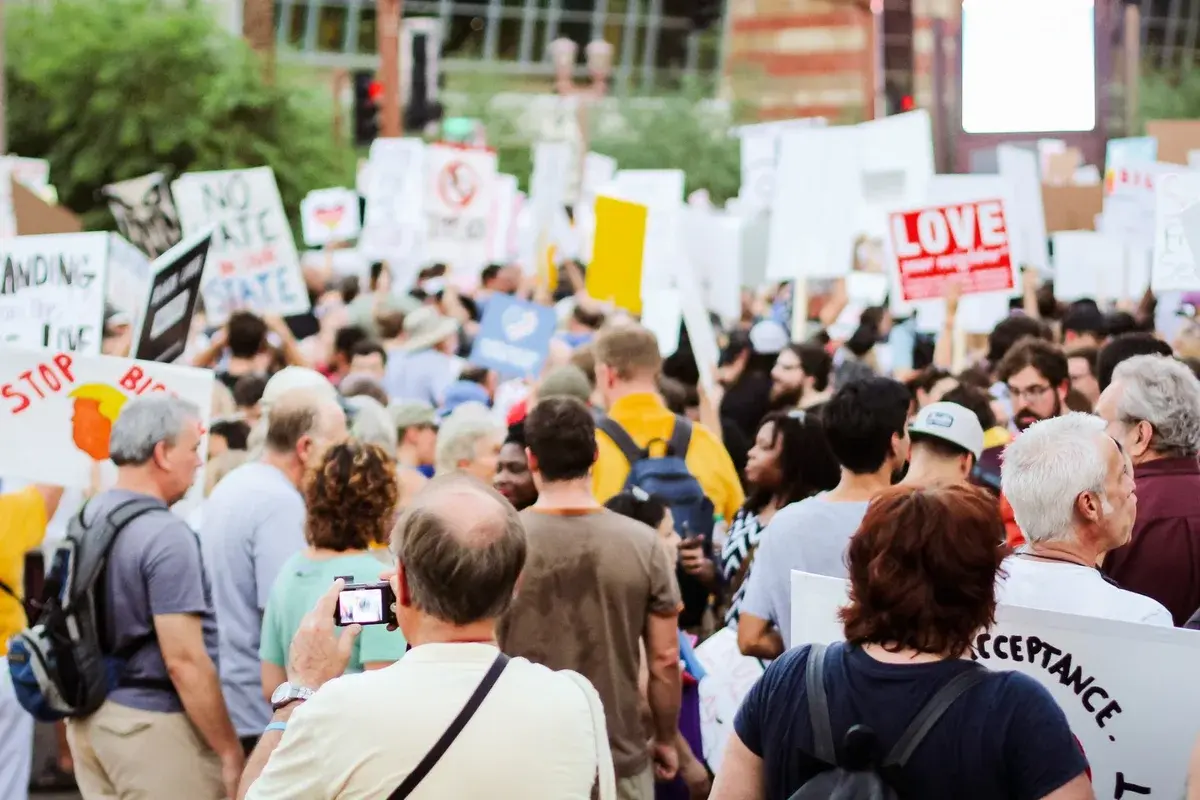 People seen from behind holding signs at a public demonstration.